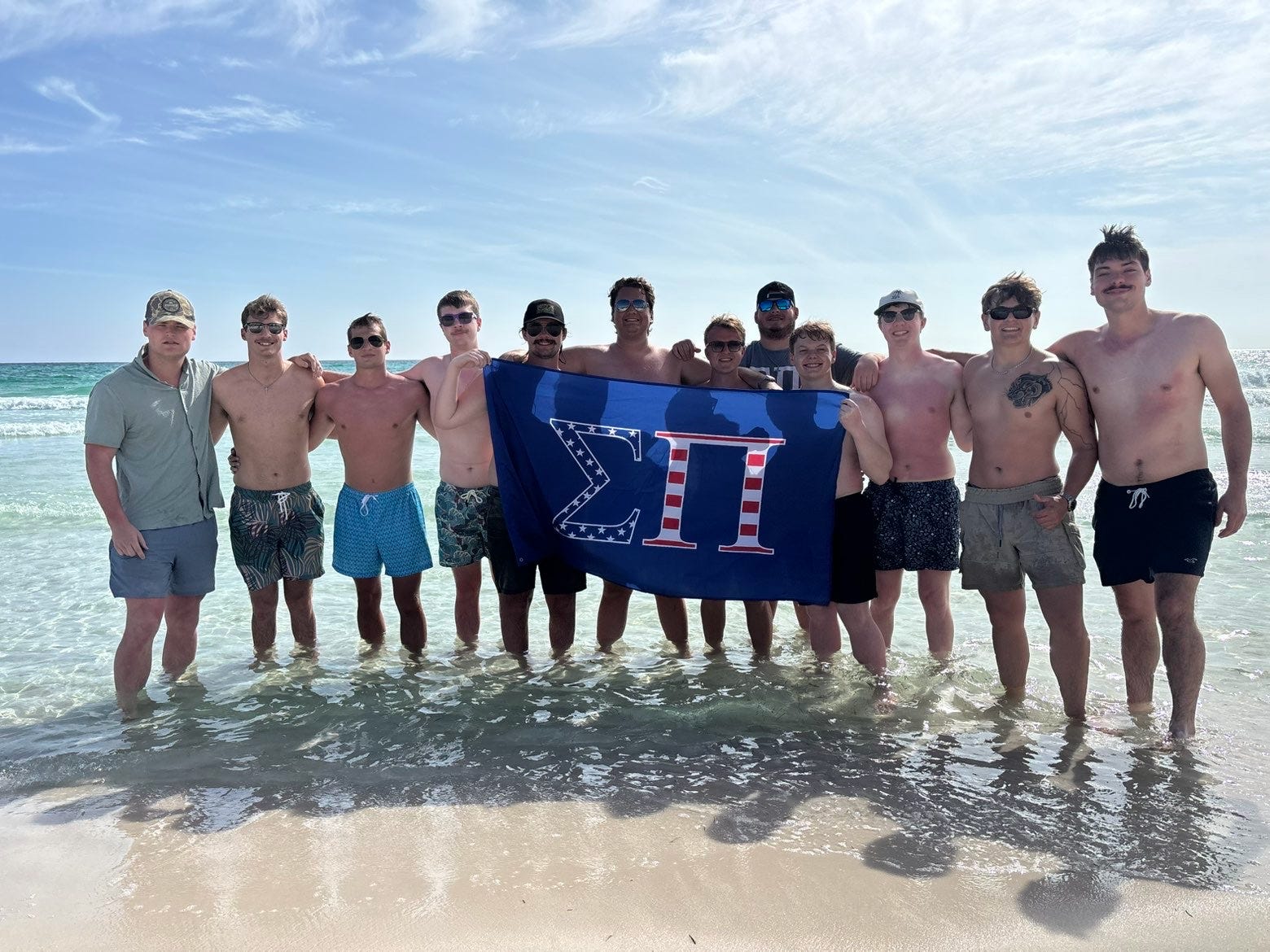 Brothers at the beach holding a Sigma Pi flag